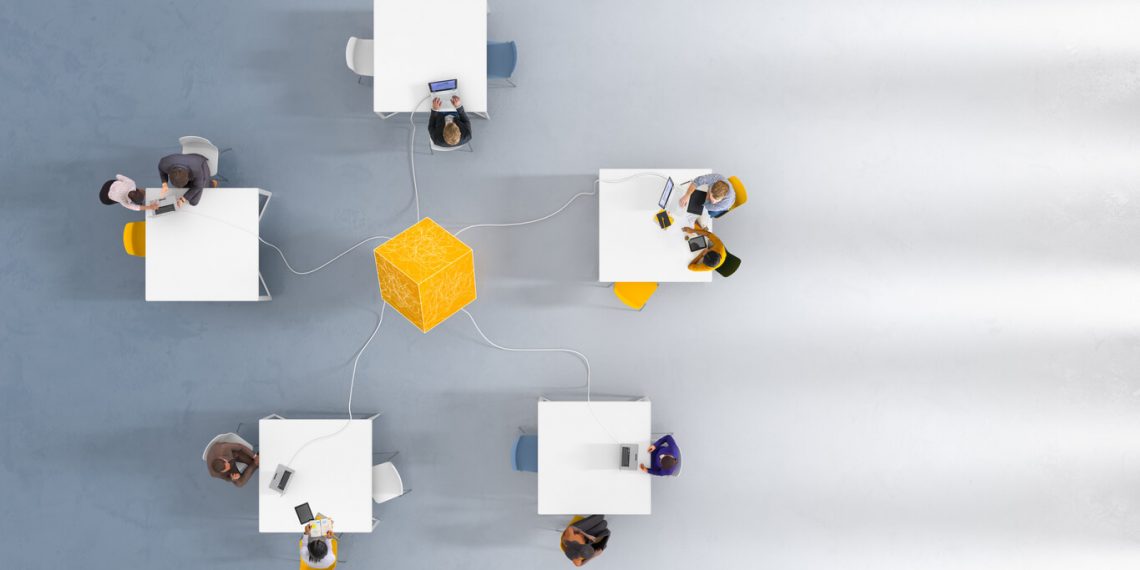 groups of people working on desks with laptops connected to blockchain