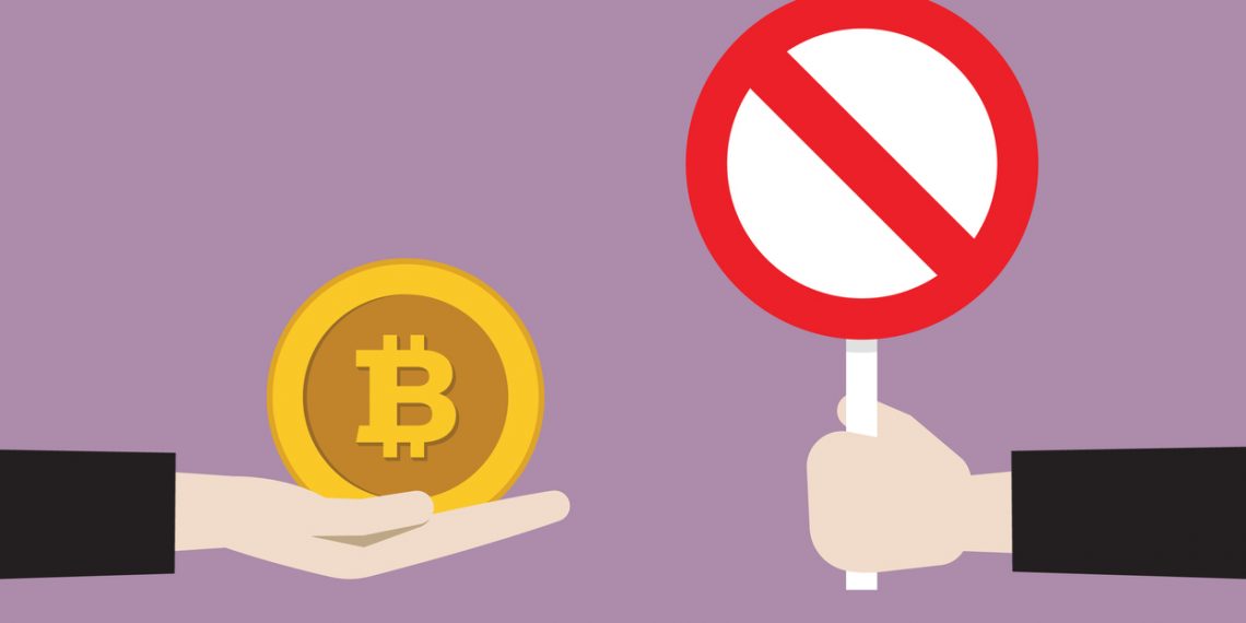 Businessman show prohibition sign to cryptocurrency coin