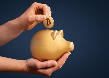 Woman inserting Bitcoin in gold piggy bank