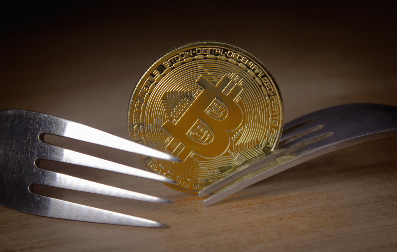 Two forks next to coin of bitcoin