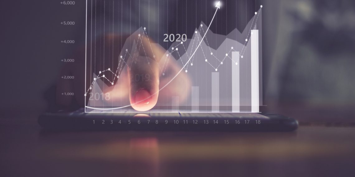 Augmented reality (AR) financial charts showing growing revenue In 2021 floating above digital screen smart phone, businesswoman having meeting about strategy for growth and success