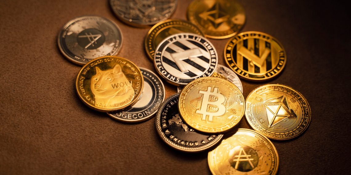 Variety of cryptocurrency coins scattered on brown background